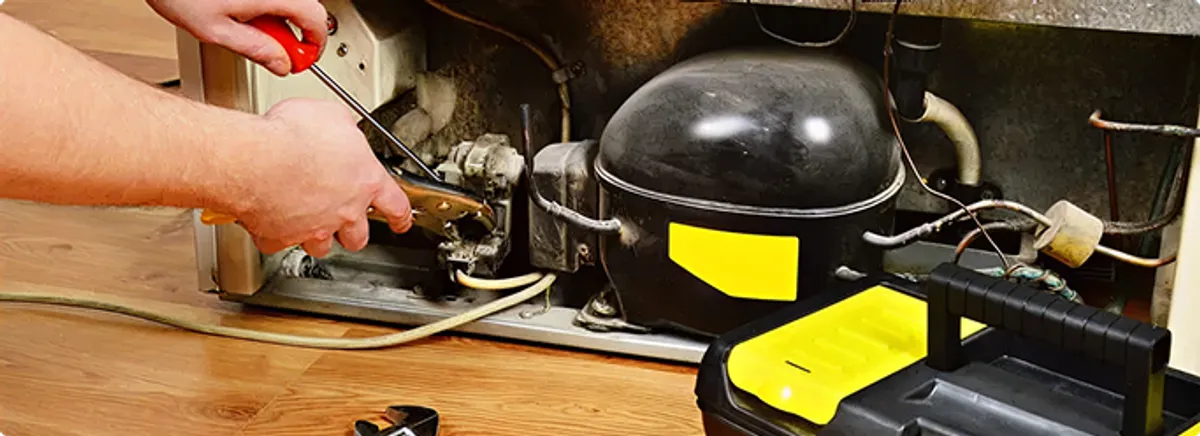 Refrigerator repair technician fixing the compressor and wiring in Heltonville, IN