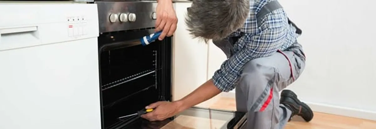 Oven repair technician inspecting and servicing an electric oven in Bloomington, IN