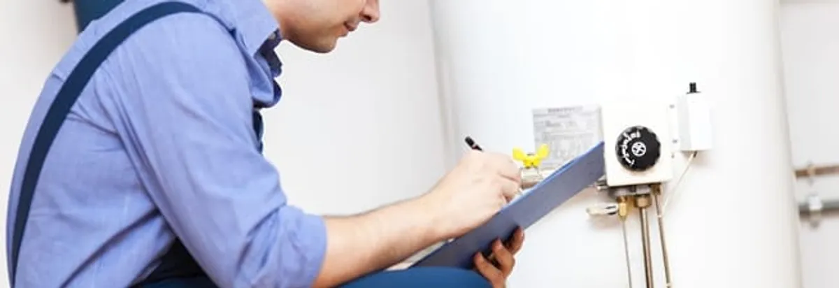 Water heater repair technician inspecting the unit and recording service notes in Bloomington, IN